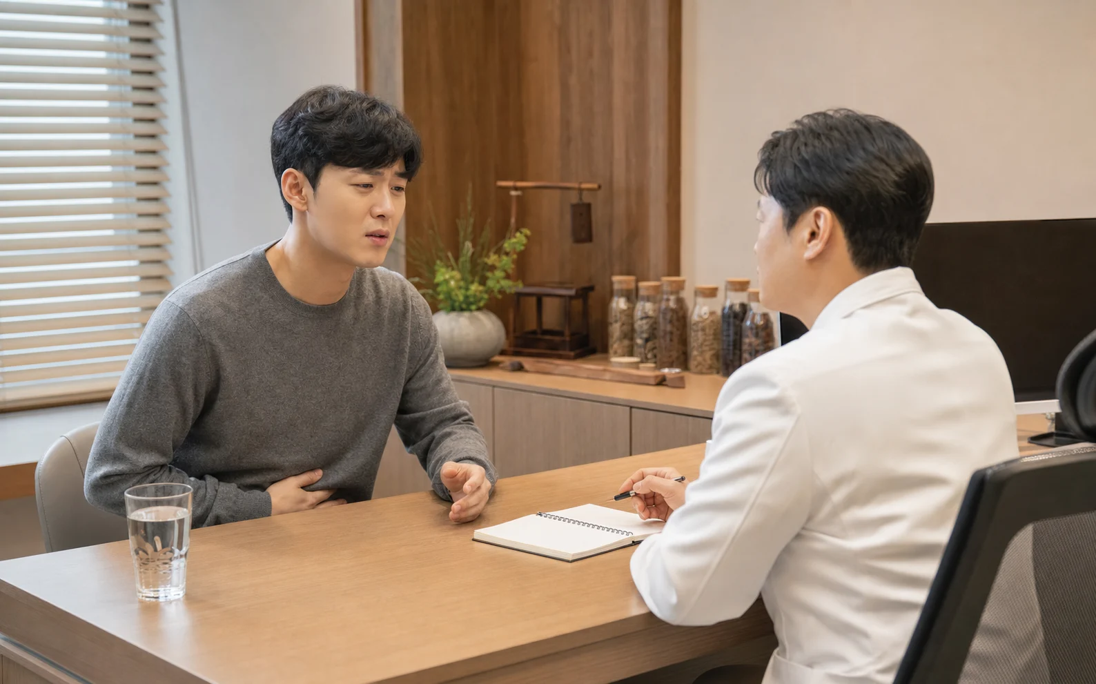 급성장염 환자가 설사와 복통, 수분 섭취 상태를 국내 한의원 진료실에서 상담하는 장면
