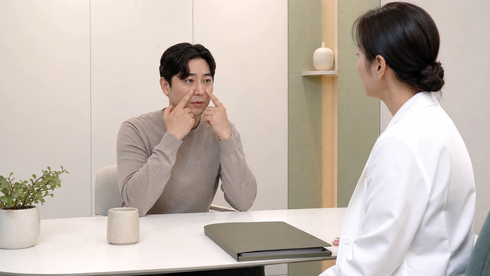 부비동염 환자가 코막힘과 얼굴 압박감을 밝은 진료실에서 상담하는 장면